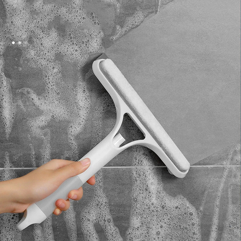 A hand holds a white multi-function window cleaning tool against a gray, textured surface.