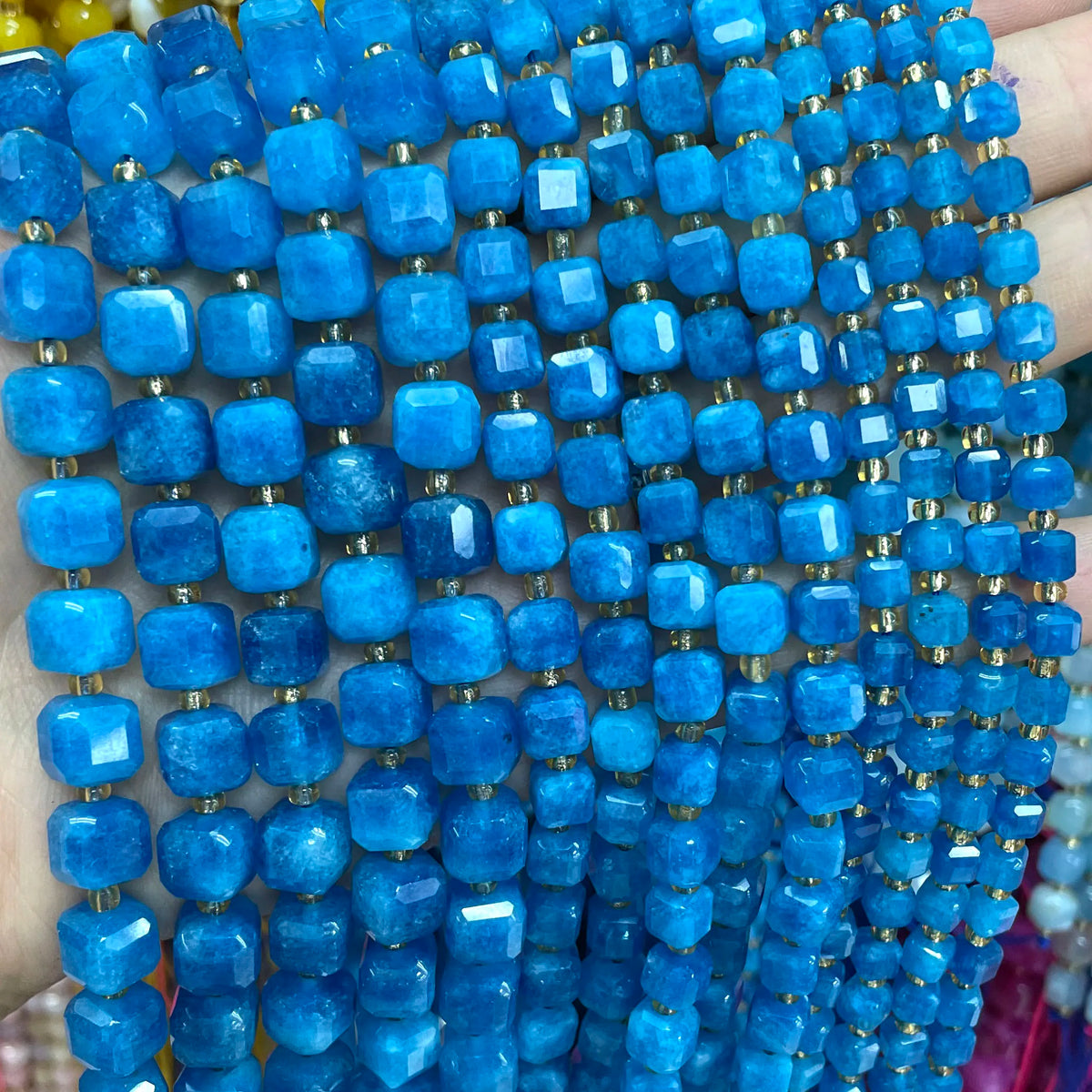 A close-up of a strand of bright blue natural stone square faceted beads for jewelry making