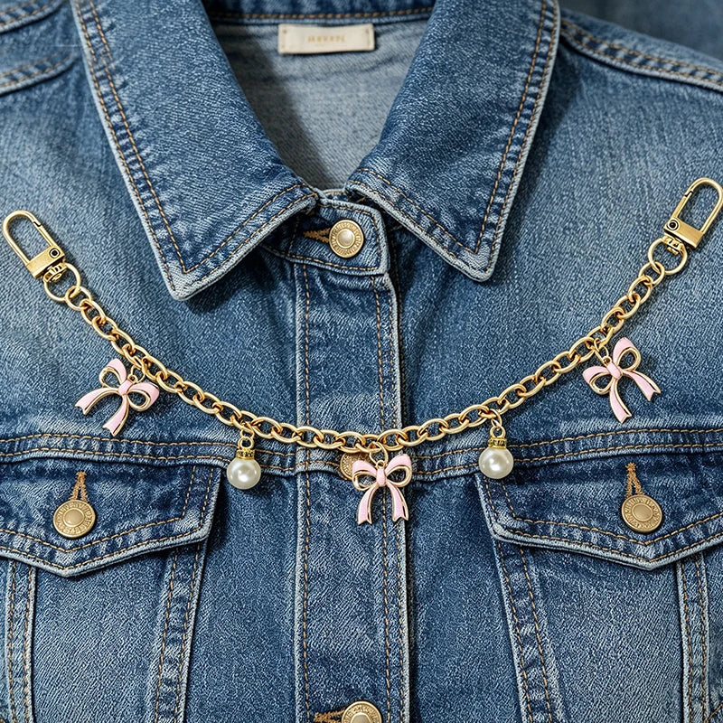 A denim jacket adorned with a gold alloy chain featuring pink bow decorations and charms.