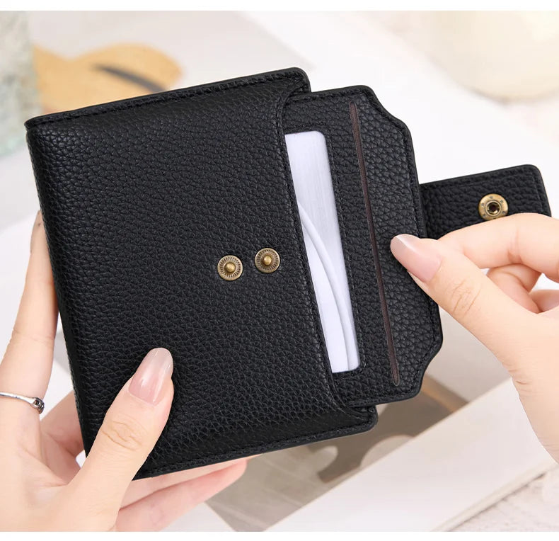 A hand holds a black compact RFID-blocking bi-fold wallet with gold accents, showing the interior card slot.