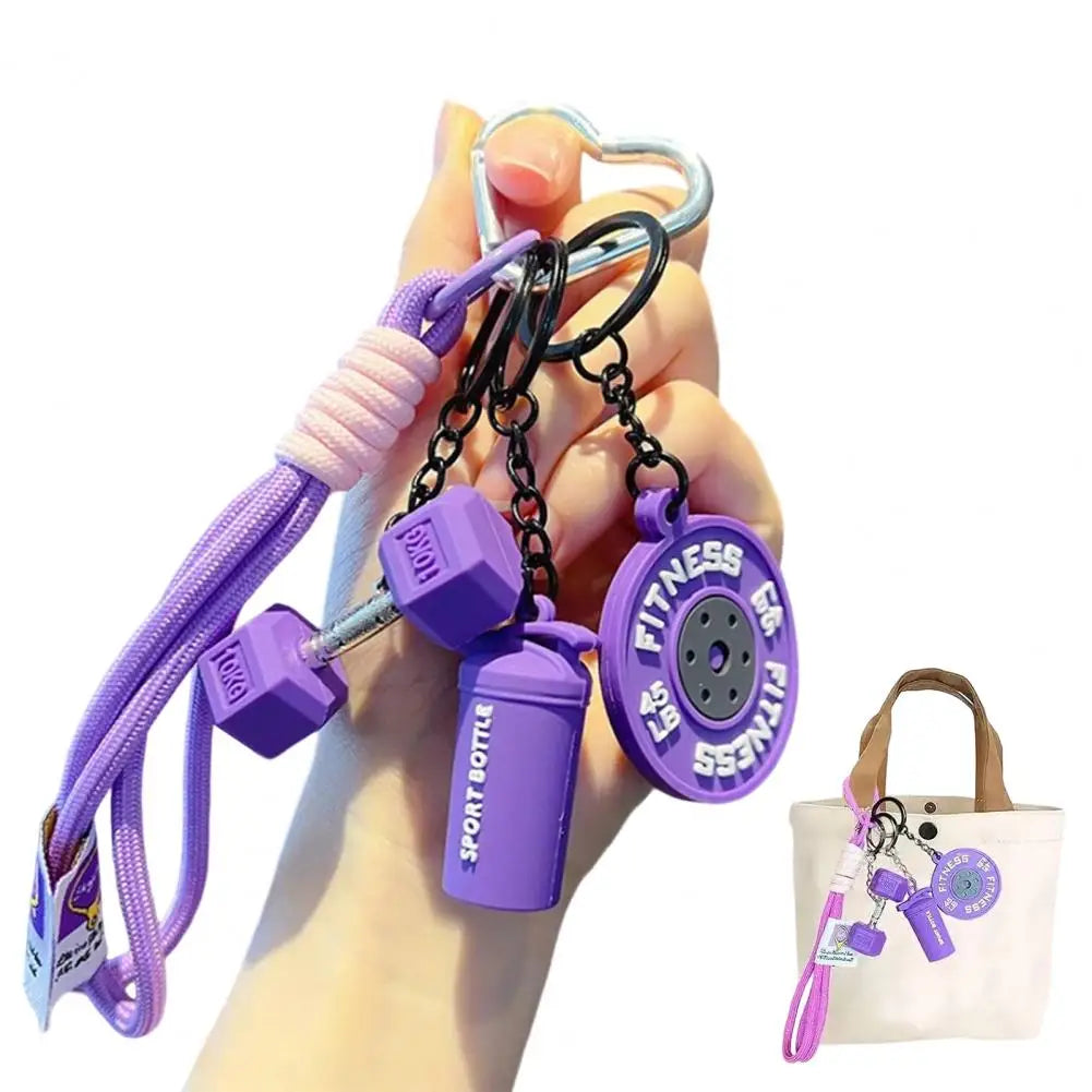 A hand holds a purple fitness keychain featuring a bottle and a fitness charm.