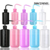 A collection of tattoo squeeze bottles in various colors including black, pink, purple, blue, and clear glass.