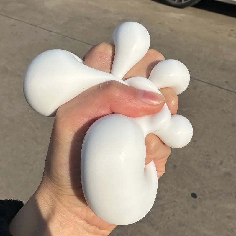 A hand is squeezing a white squishy milk tofu stress relief fidget toy.