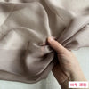 Close-up of beige silk chiffon fabric being gathered by a hand