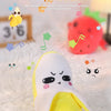 A yellow fruit-shaped plush toy resembling a lemon is shown on a white fluffy surface.