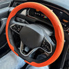 Orange breathable leather steering wheel cover installed in a car interior.