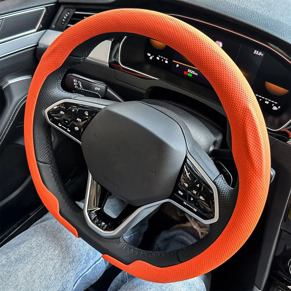 Orange breathable leather steering wheel cover installed in a car interior.