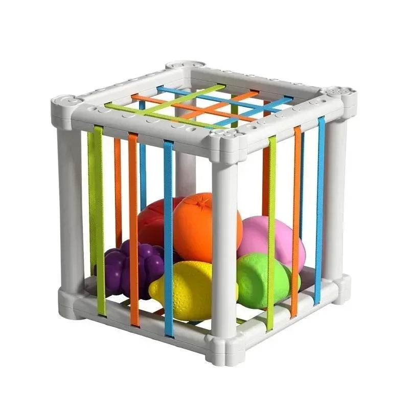 A white cube sorter with colorful elastic bands and balls for a Montessori learning toy.