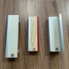 A set of wooden fingerboard ramps featuring a quarter pipe and rail, displayed on a wooden surface.