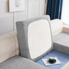 A close-up of a gray stretch jacquard sofa cover with an anti-slip backing and a white cushion on a light beige sofa.