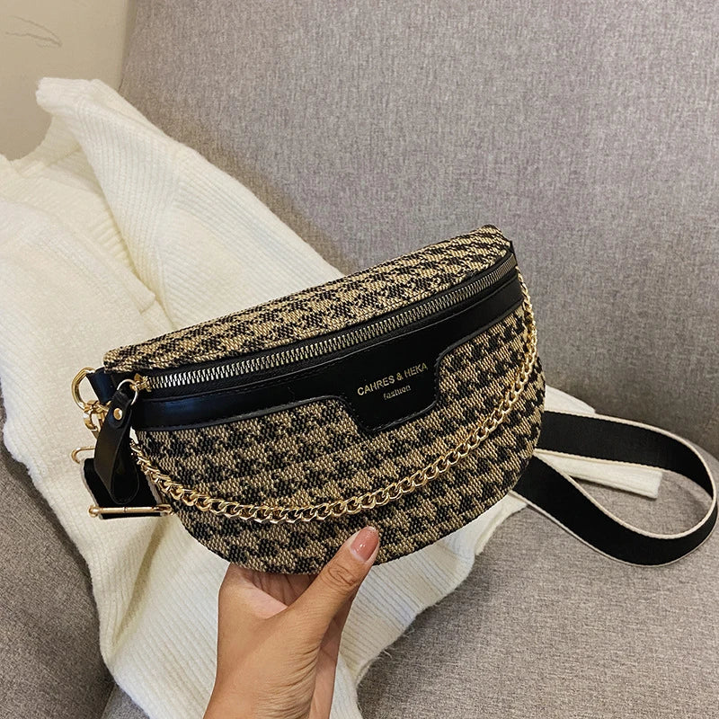 Schwarze und goldene Leopardenmuster-Crossbodytasche auf weißem Strick auf grauem Sofa.