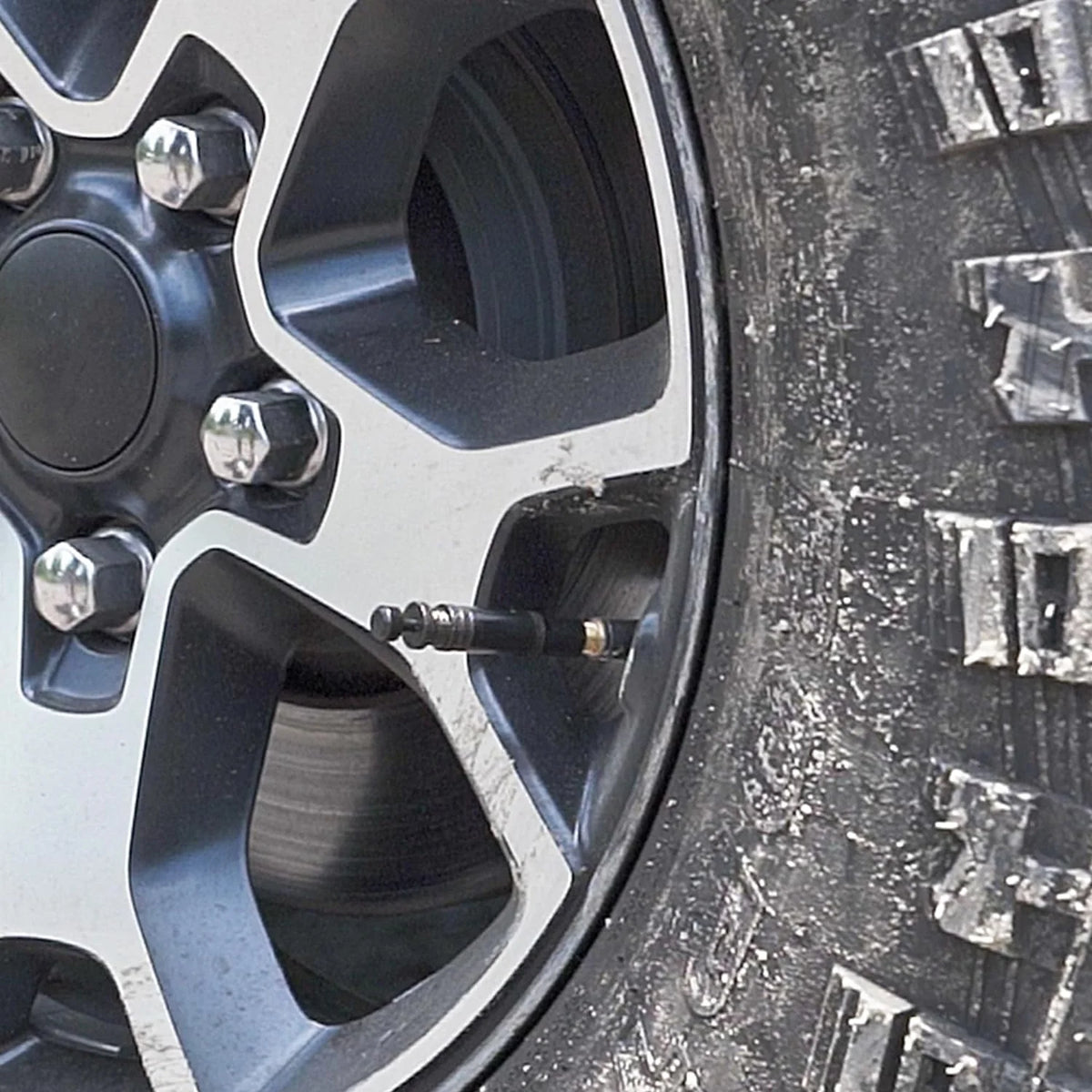 Close-up view of a tire rim with an adjustable auto-stop tire deflator kit installed.