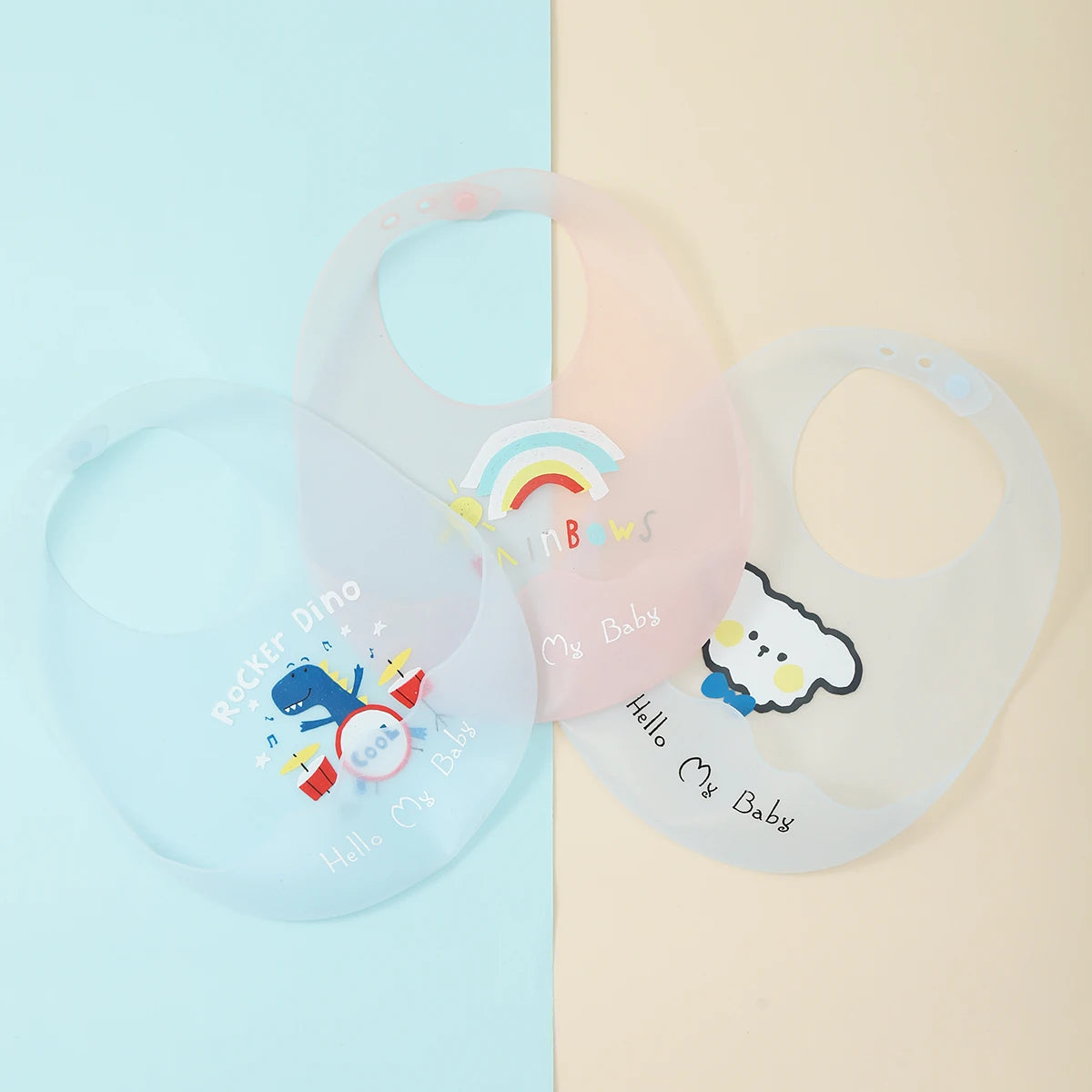 A translucent silicone baby bib featuring a rainbow and cute animal print on a light pink background.
