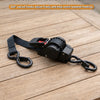 Black ABS plastic body auto-retractable ratchet tie-down straps with swivel hooks on a wooden surface.