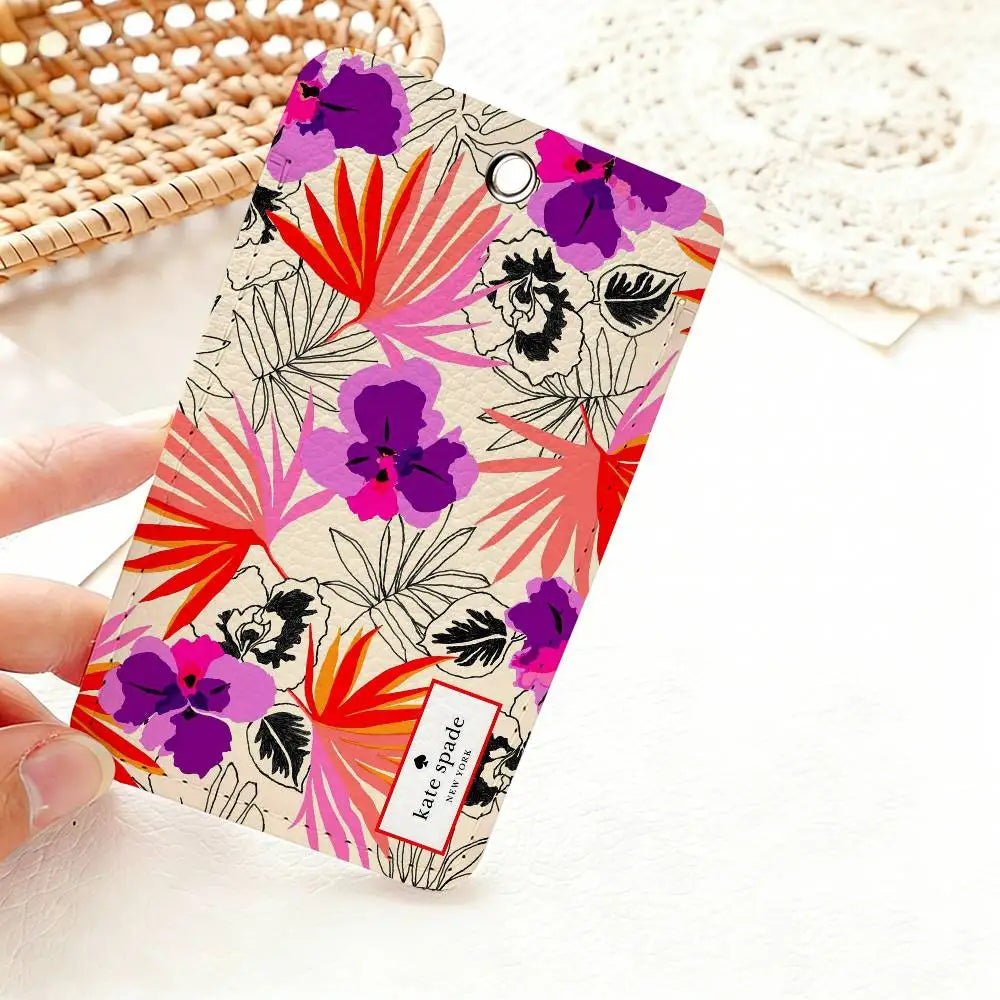A pink and purple floral pattern card holder featuring hibiscus and leaves is held by a hand on a white surface.