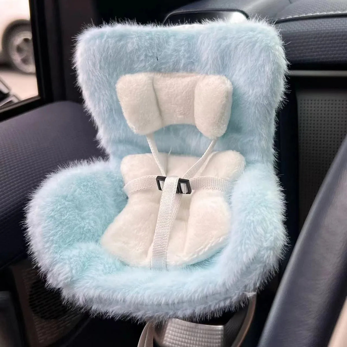A light blue faux fur seat car vent decoration with white padding and straps.