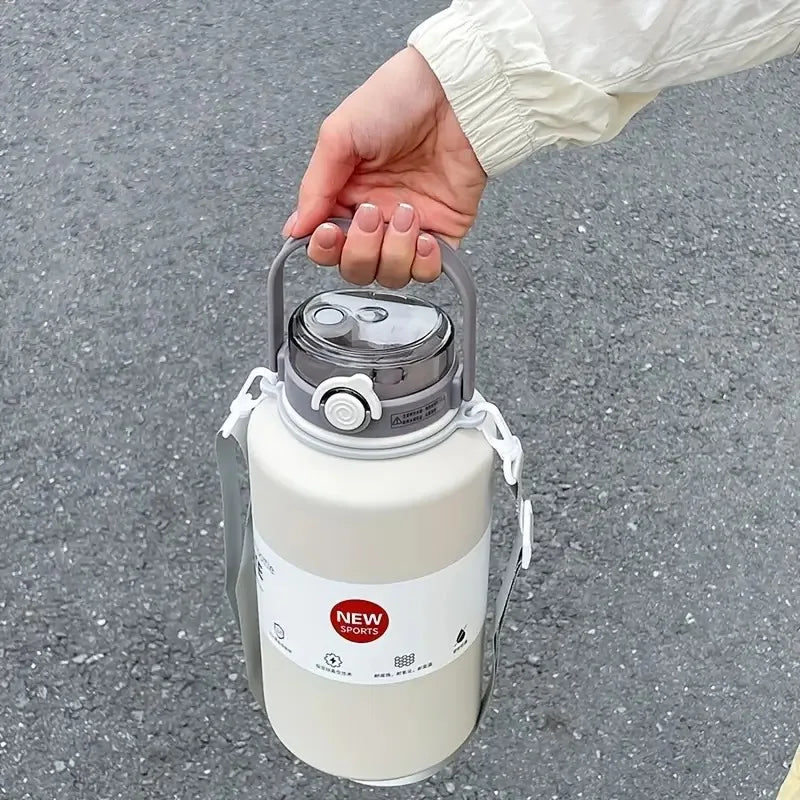 A hand is holding a white insulated stainless steel tumbler with a lid and straw on an asphalt surface.