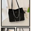 Black crystal-embellished chain shoulder bag displayed on a white surface.
