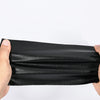 A hand is holding a black self-adhesive PU leather repair patch, showing its texture and thickness.