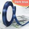 Dark blue satin ribbon roll with gold edges displayed on a surface.