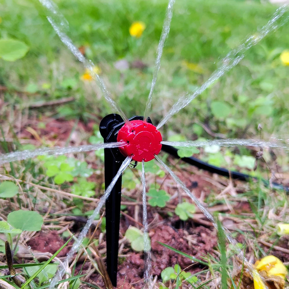 A portable micro drip irrigation kit is shown with water spraying out in a star pattern onto the ground.