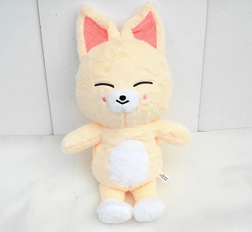 A soft yellow and white plush toy resembling a fox or canine character with closed eyes.