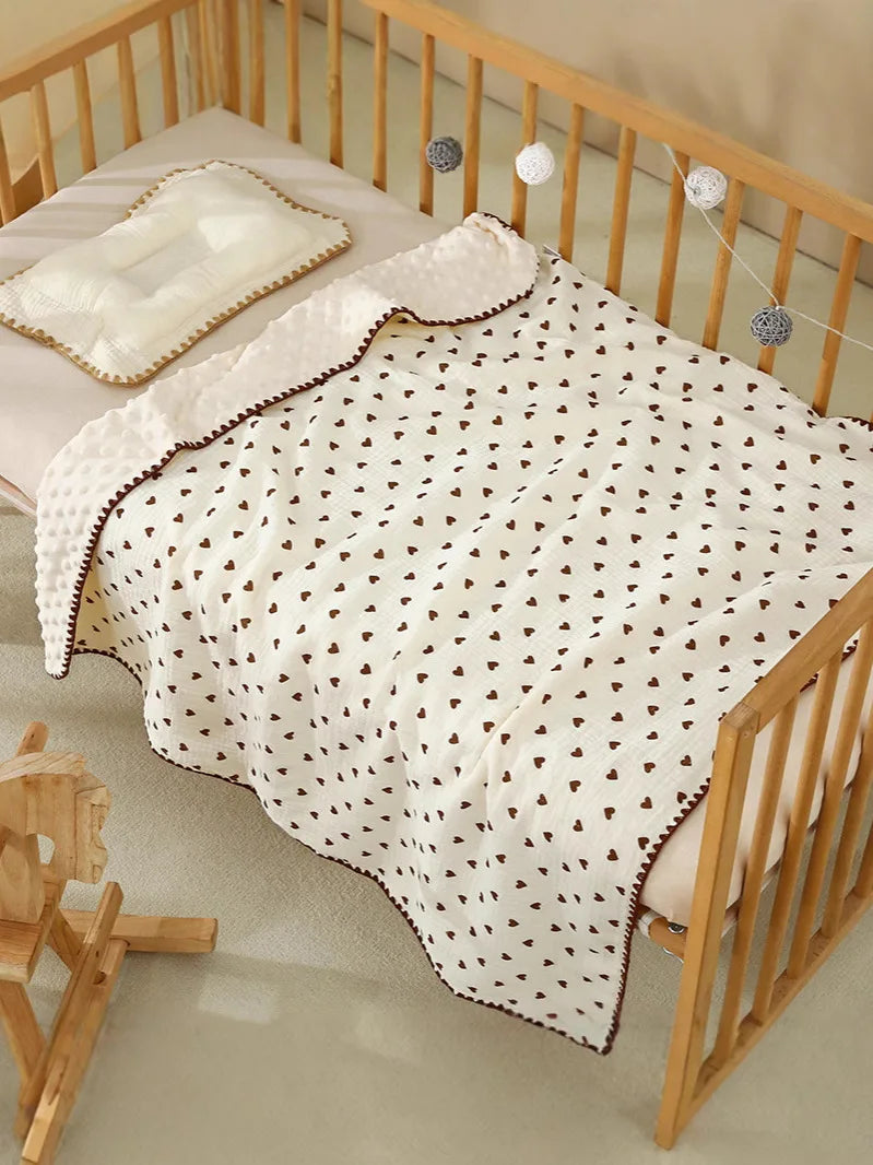 A white baby swaddle blanket with a bear print pattern is displayed on a wooden crib railing.