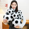 A woman holds a cluster of realistic black and white football plush pillows.