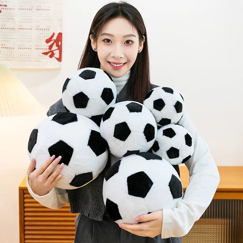 A woman holds a cluster of realistic black and white football plush pillows.
