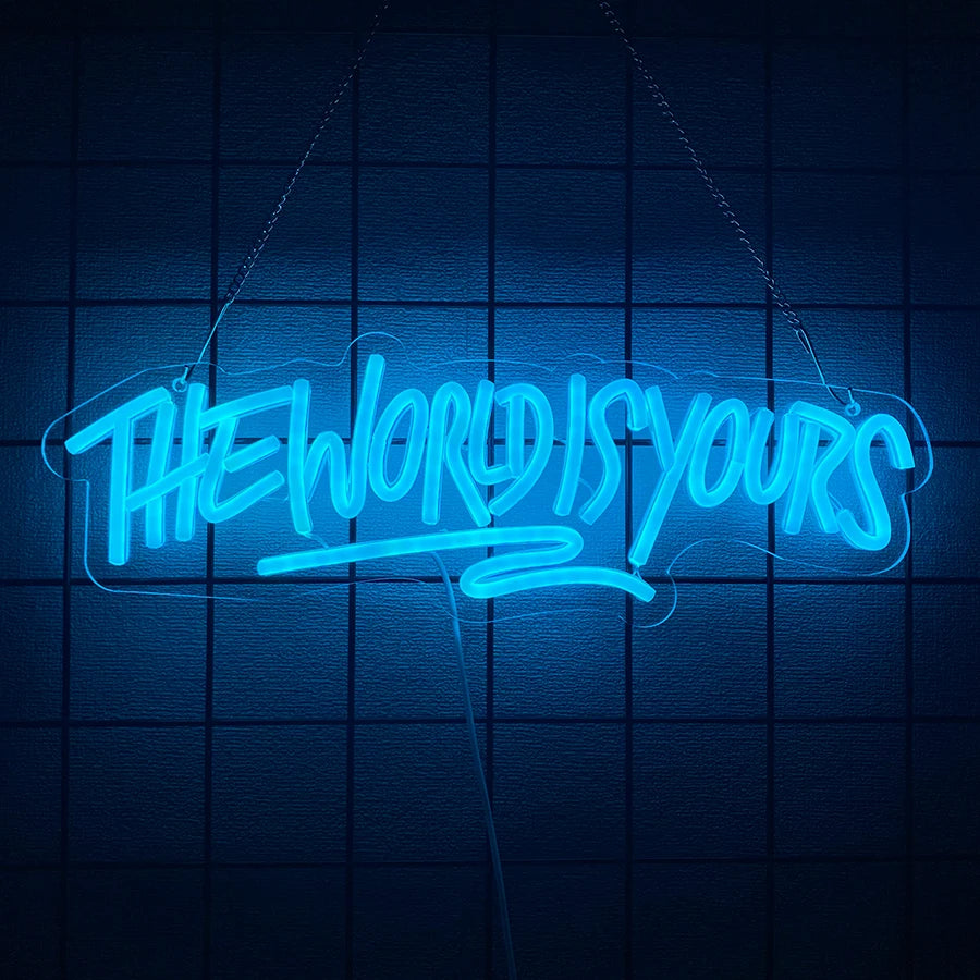 A glowing blue neon sign shaped like the words THE WORLD IS YOURS is suspended against a dark grid background.