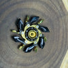 A precision metal fidget spinner with black and gold accents resting on a wooden surface.