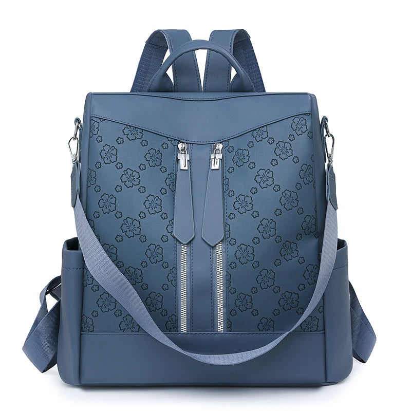 A navy blue anti-theft leather backpack with a floral pattern and adjustable straps.