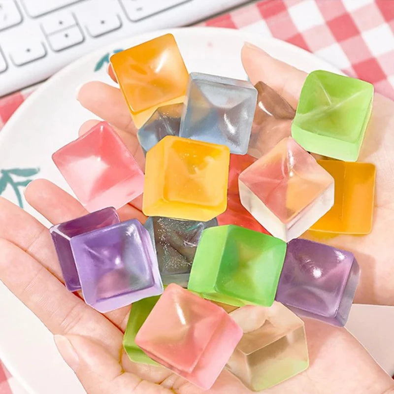 A hand holds a collection of colorful squishy ice cube fidget toys and sensory balls.
