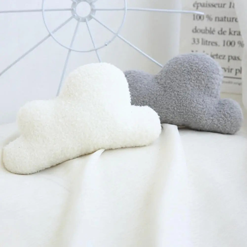 Two cloud-shaped plush pillows in white and gray resting on a white surface.