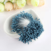 A cluster of 400 pearl flower stamens in blue and white are displayed in a white dish.
