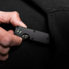 A hand holds a minimalist black aluminum key organizer with a small opening for holding keys.