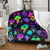 A colorful mushroom print flannel throw blanket draped over a white sofa.