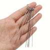 A hand holds a set of ten stainless steel shower head cleaning brushes with long, thin wires.