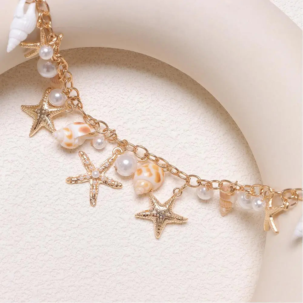 Gold chain accessory featuring starfish charms and white pearls on a light background.
