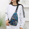 A woman wearing a white sweatshirt holds a blue and green leaf print sling crossbody bag.