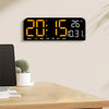 A black digital wall clock displaying the time 20:15 and a temperature of 26 degrees on a wooden desk.