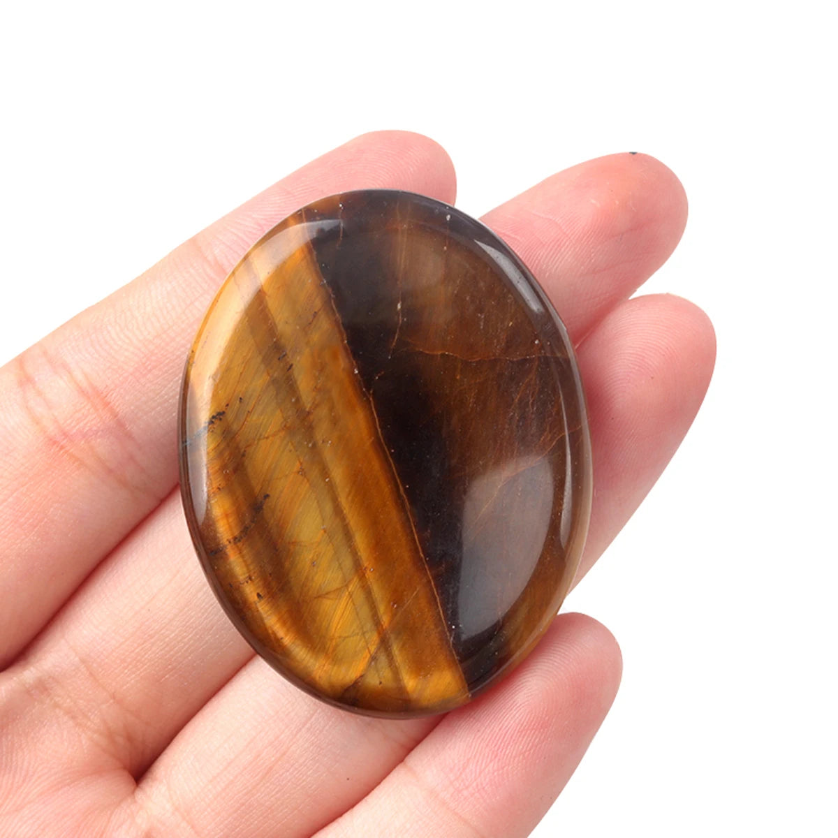 A smooth, oval amber-colored crystal stone is held in a person's hand.