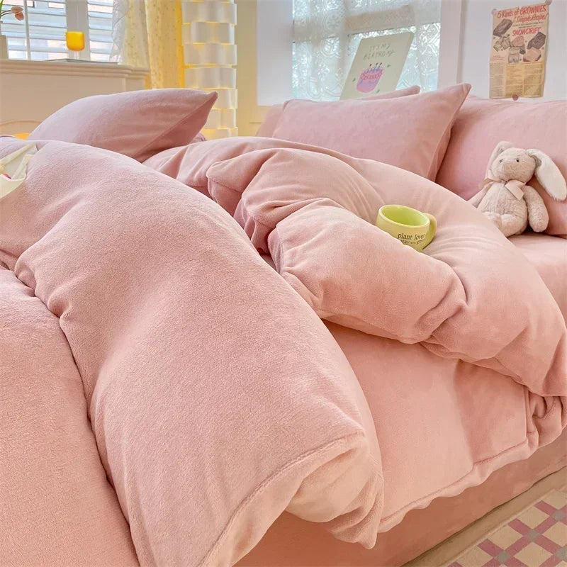 A pink velvet bedding set featuring a duvet cover and pillows with a small stuffed rabbit toy.