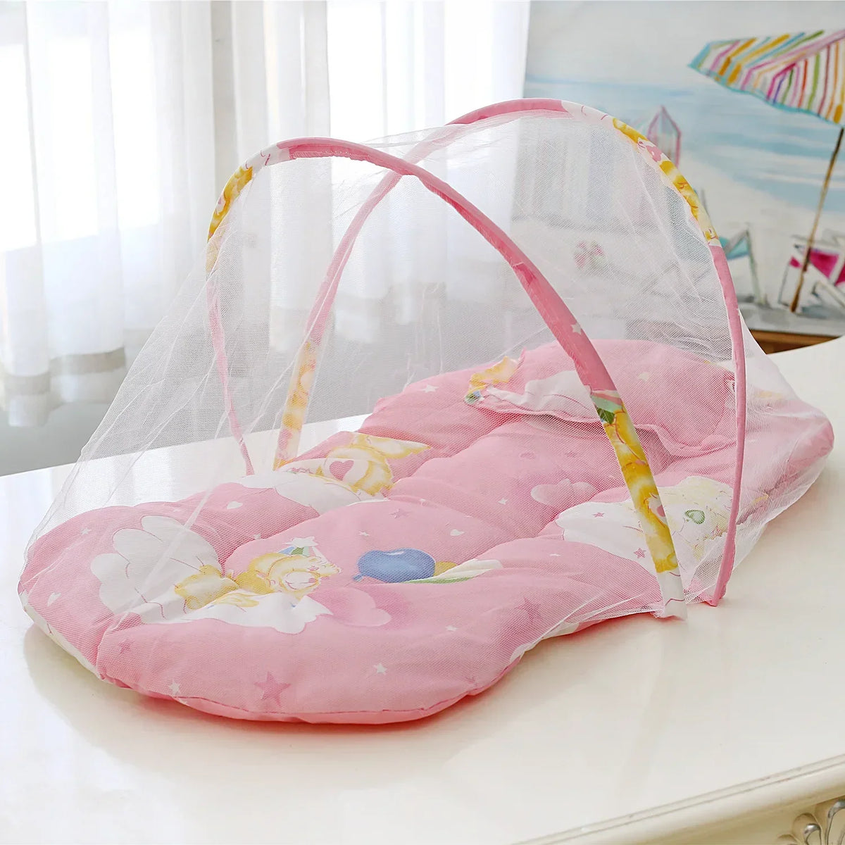 A pink portable crib mosquito net with a pillow and cotton pad is displayed on a white surface.
