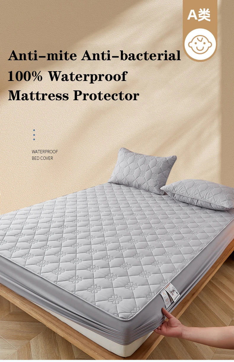 A gray waterproof mattress protector is shown on a bed, folded and displayed next to a pillow.
