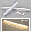 A white motion sensor LED night light bar with a USB charging cable and a warm light glow.