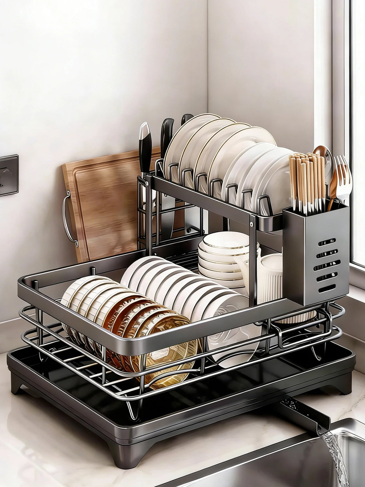 A black two-tier kitchen countertop drying rack holding stacks of white and brown plates and cutlery.