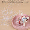 A pink silicone sensory rattle ball for baby development is shown on a light pink plate with scattered silicone pieces.