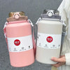 A pink insulated stainless steel tumbler with a lid and straw is held by a person.
