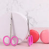 A pair of professional stainless steel cuticle scissors with curved blades resting on a pink surface.